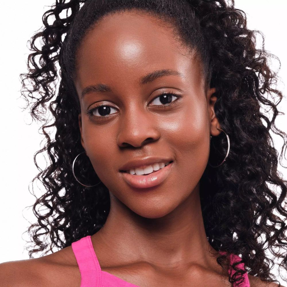 Portrait d'une femme aux cheveux bouclés et boucles d'oreilles. Elle porte un haut rose.