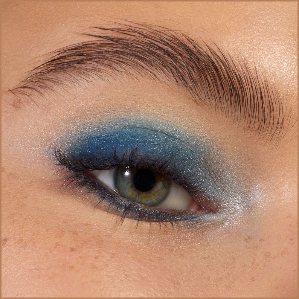 Gros plan sur un œil avec fard à paupières bleu. Sourcil, cils, peau. Fond naturel.