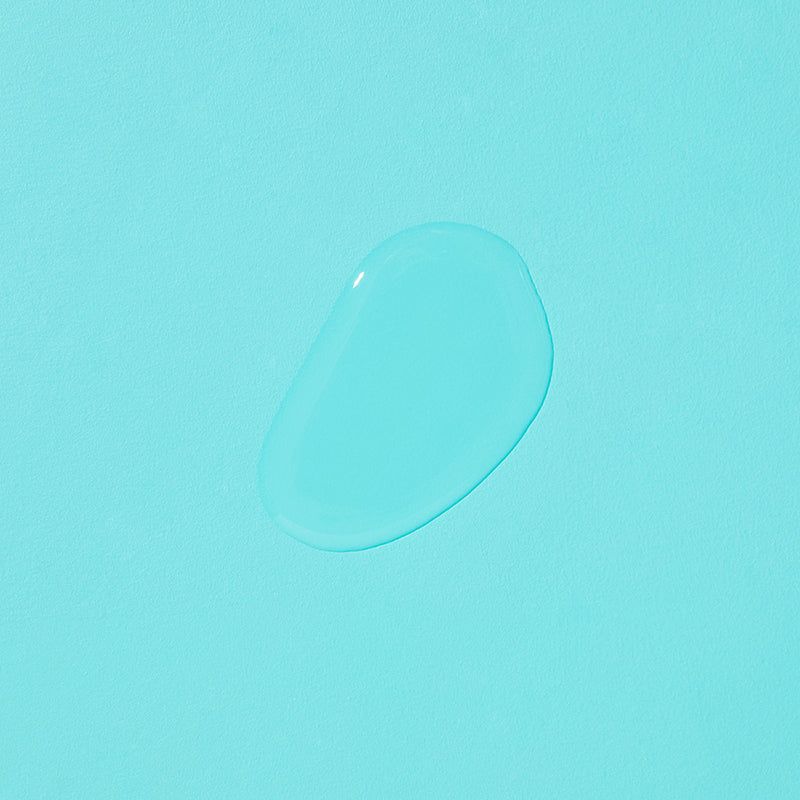 Druppel heldere vloeistof op lichtblauwe achtergrond. Geen verpakking of label zichtbaar.