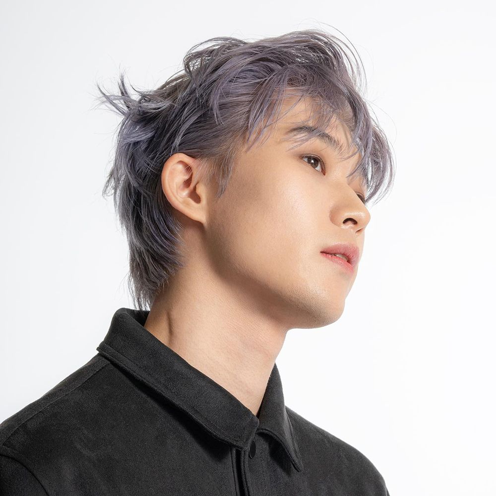 Portret van een man met grijs geverfd haar. Hij draagt een zwart overhemd en kijkt opzij.