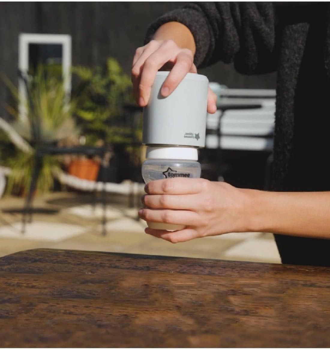 Een witte babyflesverwarmer wordt op een Tommee Tippee fles geplaatst.