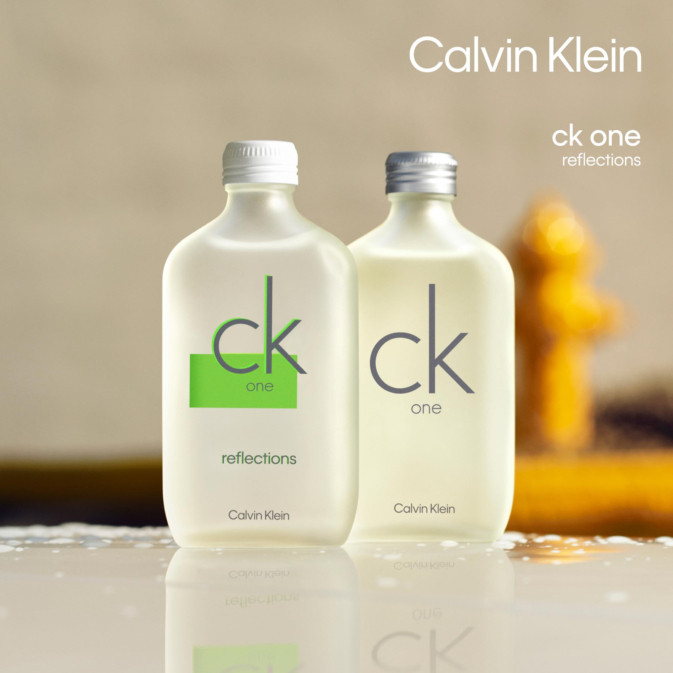 Twee CK One Reflections flessen met witte en zilveren dop. Opschrift CK One Reflections.