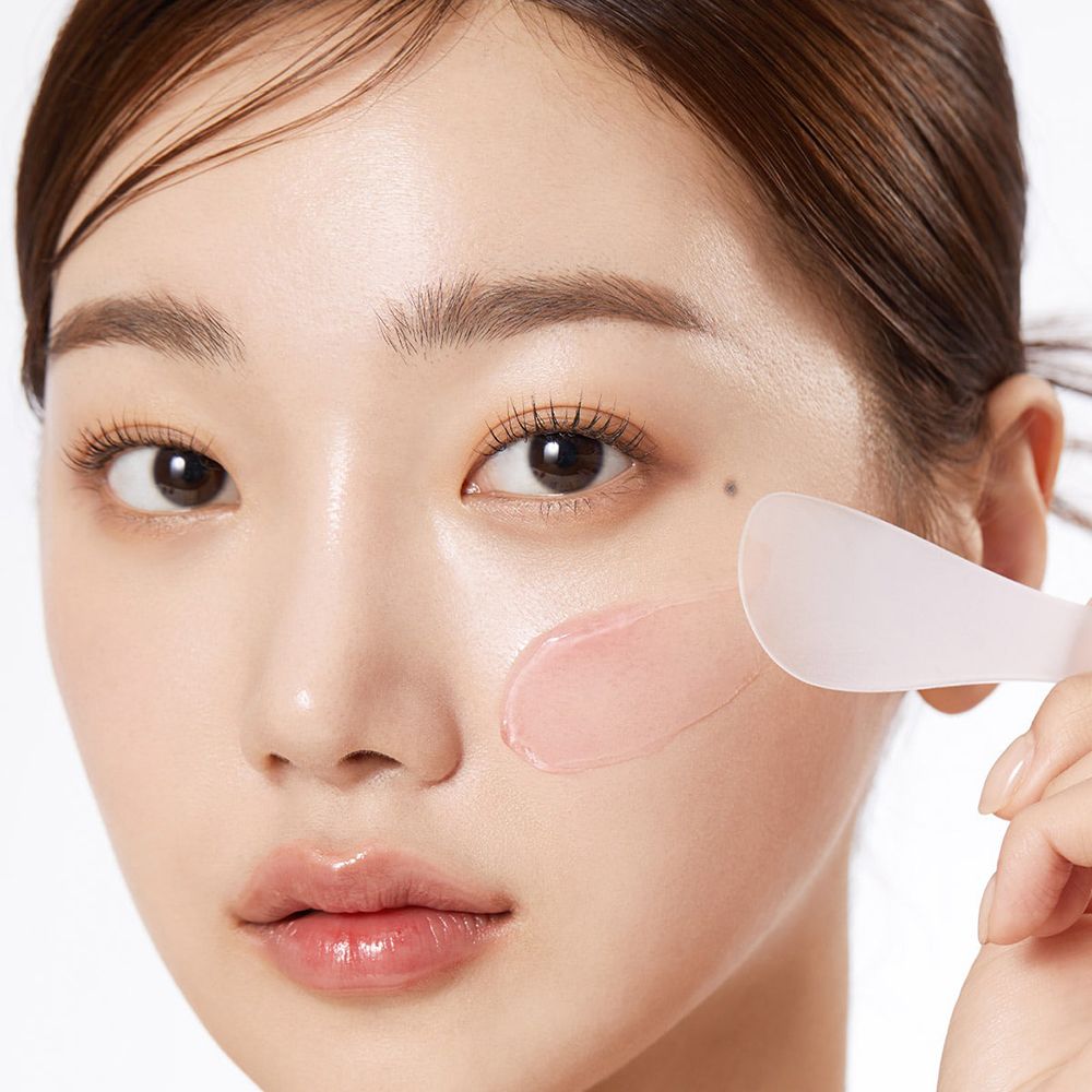 Gezicht van een vrouw. Roze gel wordt met een spatel aangebracht.