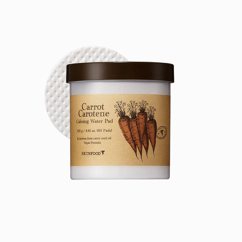 Pot avec inscription "Carrot Carotene Calming Water Pad". Couvercle marron, étiquette avec illustration de carottes. Pad de coton à côté.
