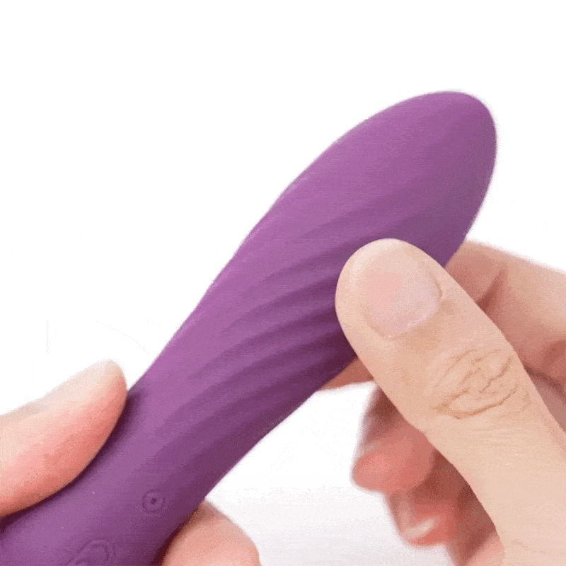 Vibrateur violet avec surface ondulée. Une main tient le produit.