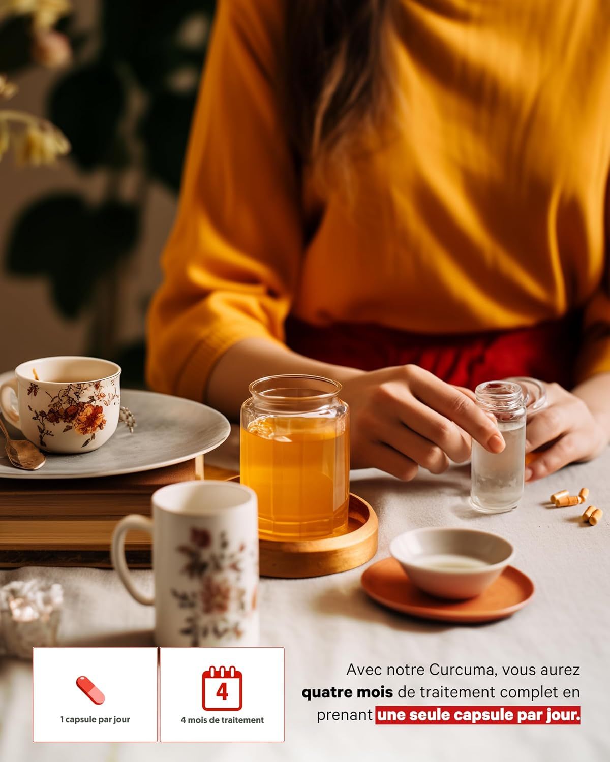 Une personne tient une petite bouteille en verre de liquide au-dessus d'une table avec une tasse, un verre et un bol.