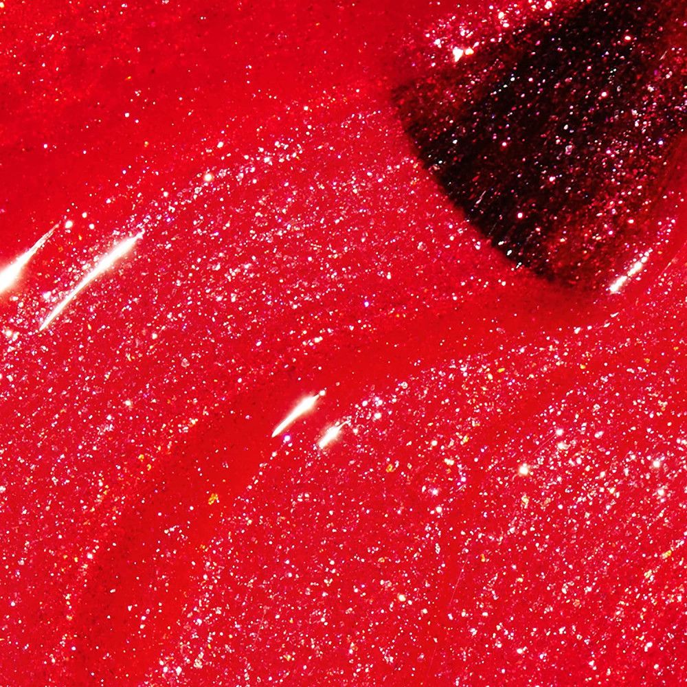 Vernis à ongles rouge pailleté. Gros plan, pointe du pinceau dans le vernis.