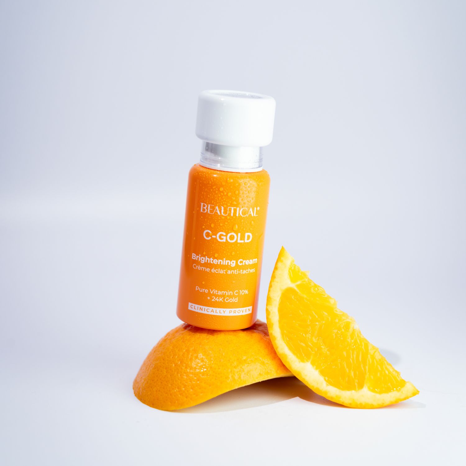 Productfles en sinaasappelschijf. Opschrift: BEAUTICAL C-GOLD Brightening Cream.