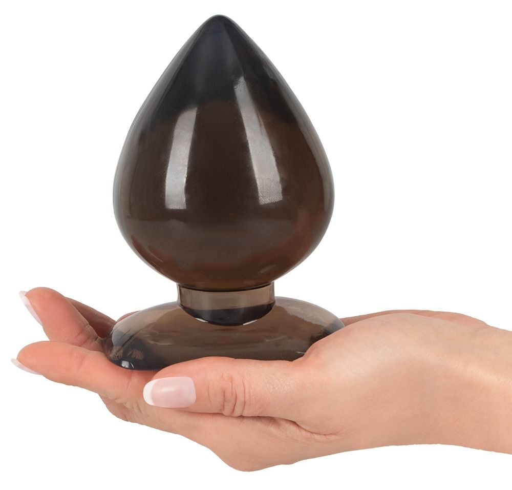 Paume tenant un plug anal en forme de goutte, en matière marron brillante.