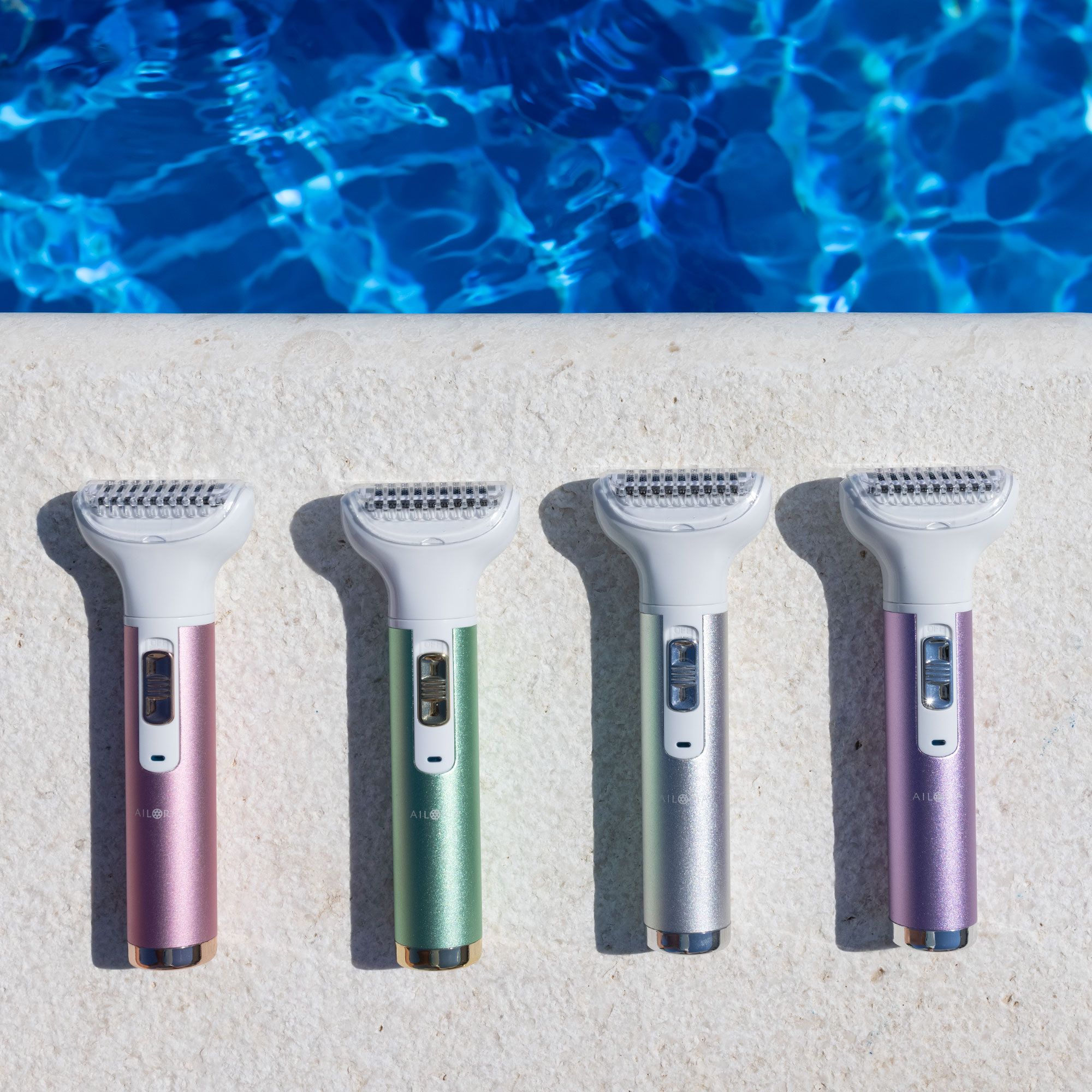 Quatre rasoirs de différentes couleurs : rose, vert, argent et violet. Tous avec une tête blanche et le logo AILORIA.