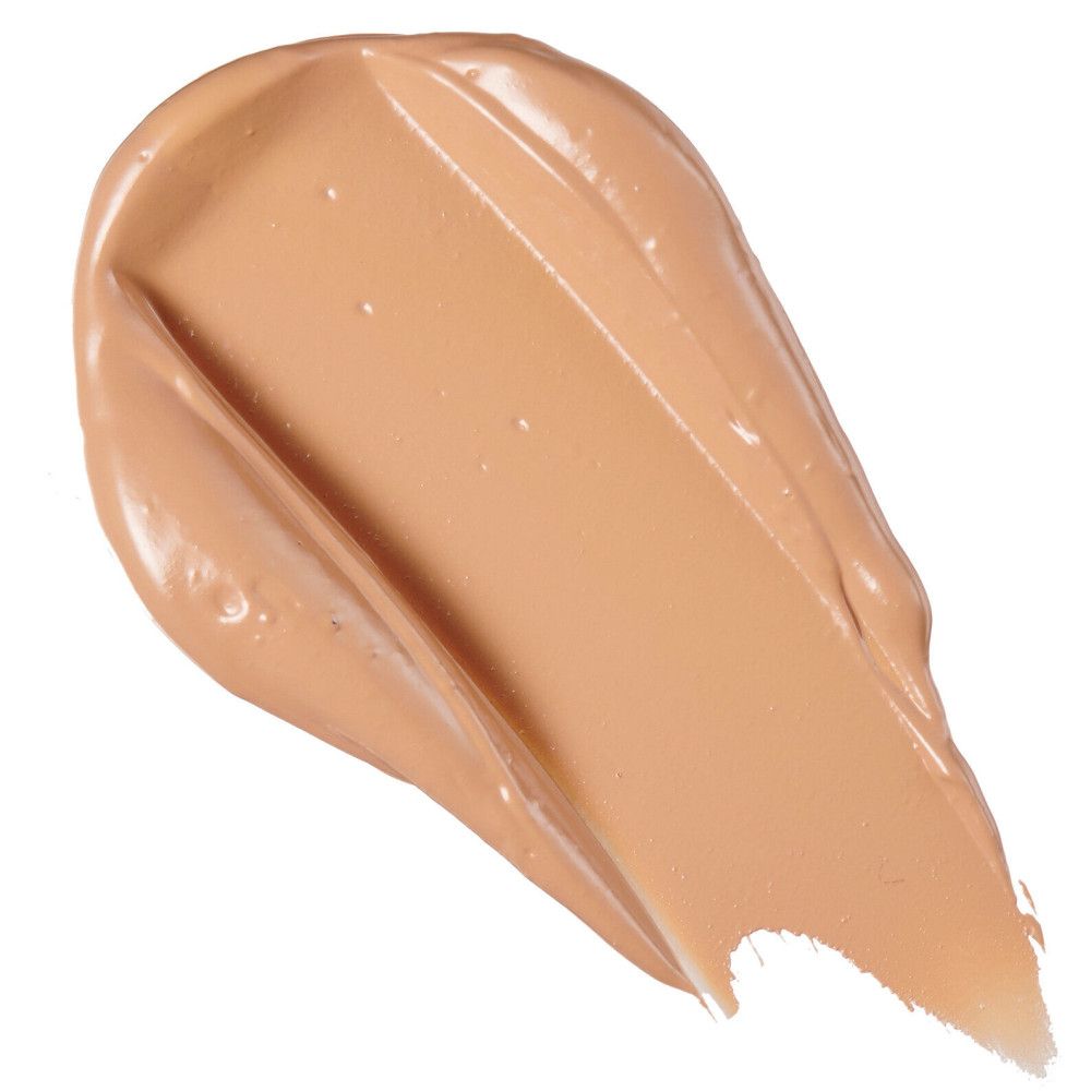 Nuance claire de correcteur sur fond blanc. Texture crémeuse, trait de pinceau diagonal.