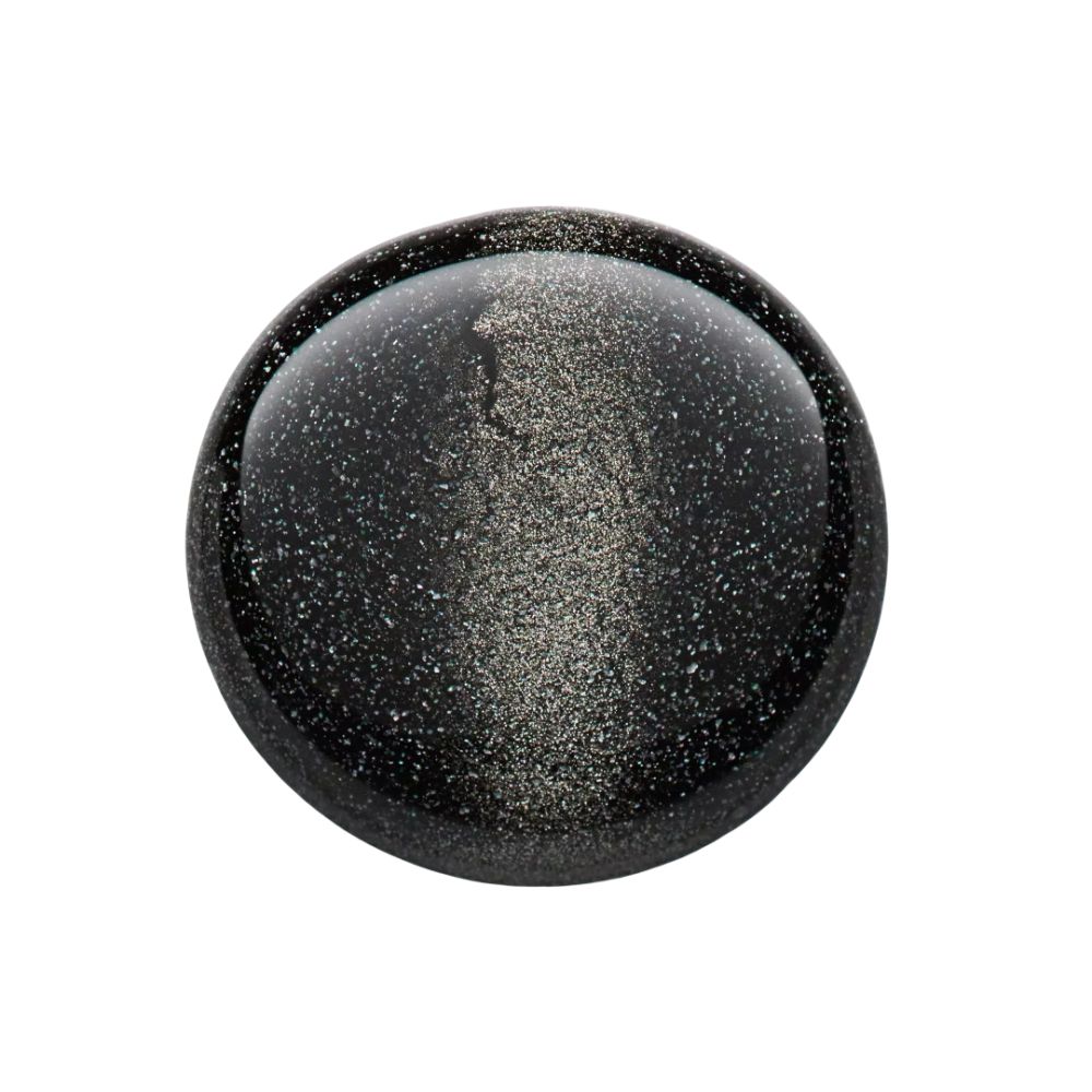 Gros plan sur une surface de vernis à ongles noir avec des particules scintillantes. Forme ronde.