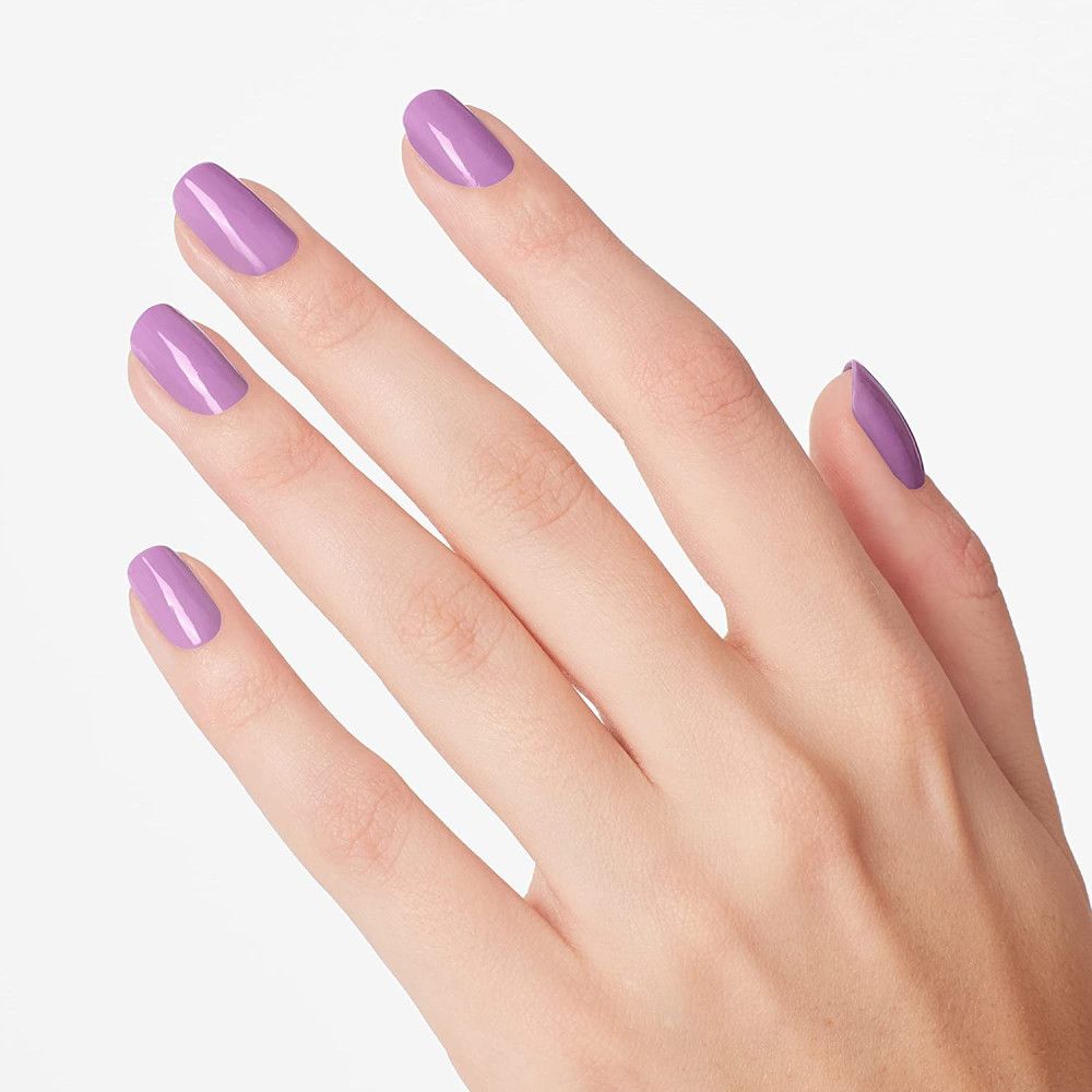 Main avec ongles vernis en violet. Cinq doigts avec ongles vernis uniformément.