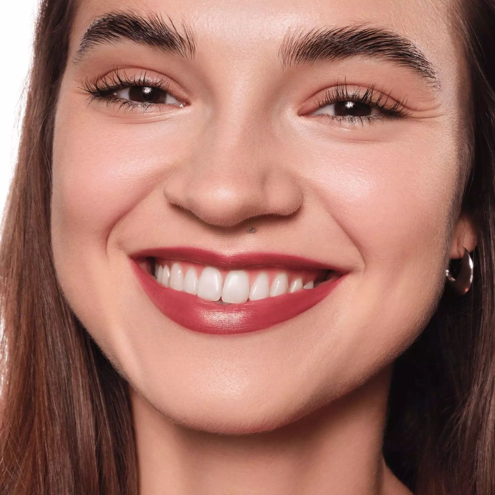 Gros plan d'un visage souriant avec du rouge à lèvres. Lèvres rouges. Femme à la peau claire et boucles d'oreilles argentées.