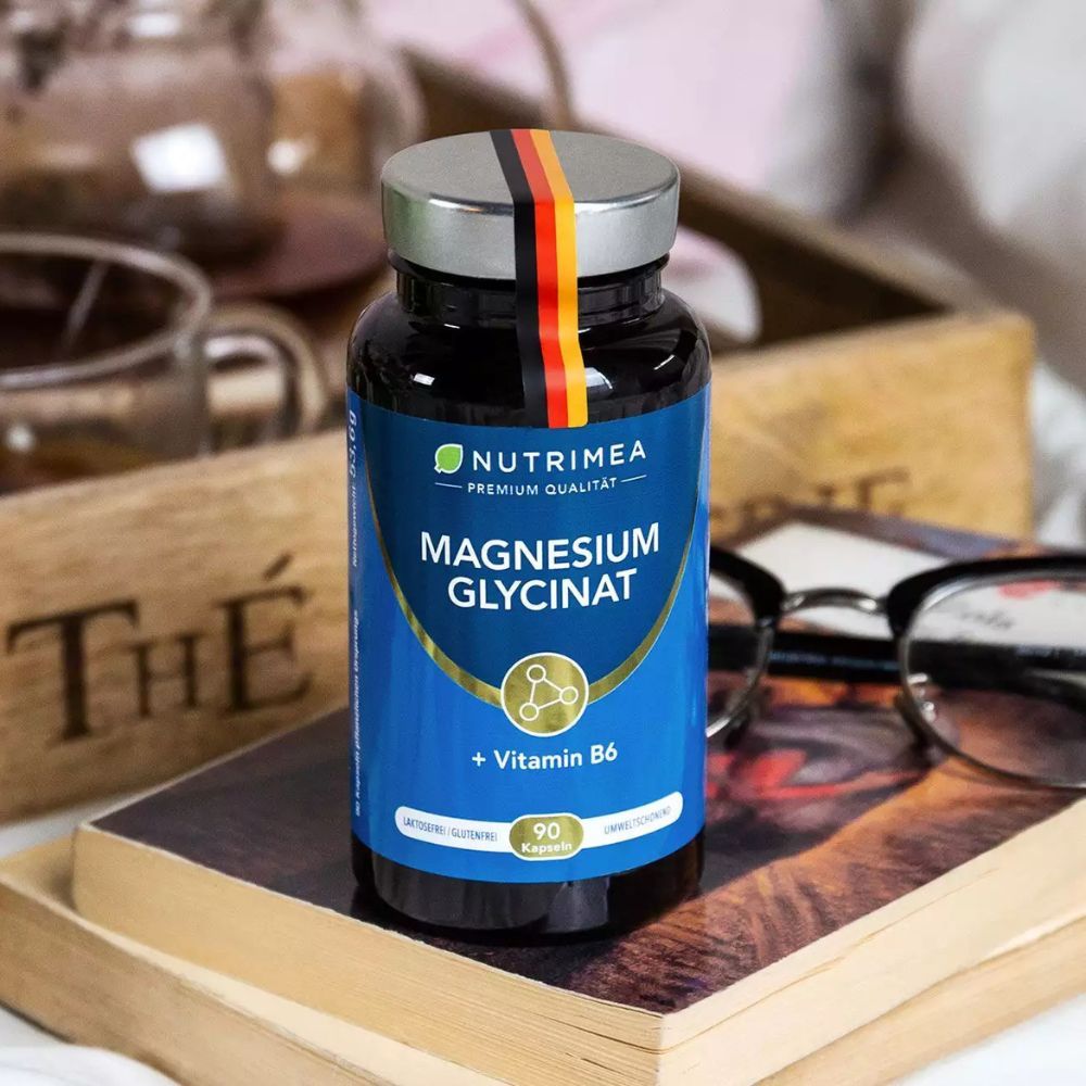 Blauwe fles op boek. Bevat Magnesium Glycinaat + Vitamine B6. Met Duitse vlag.