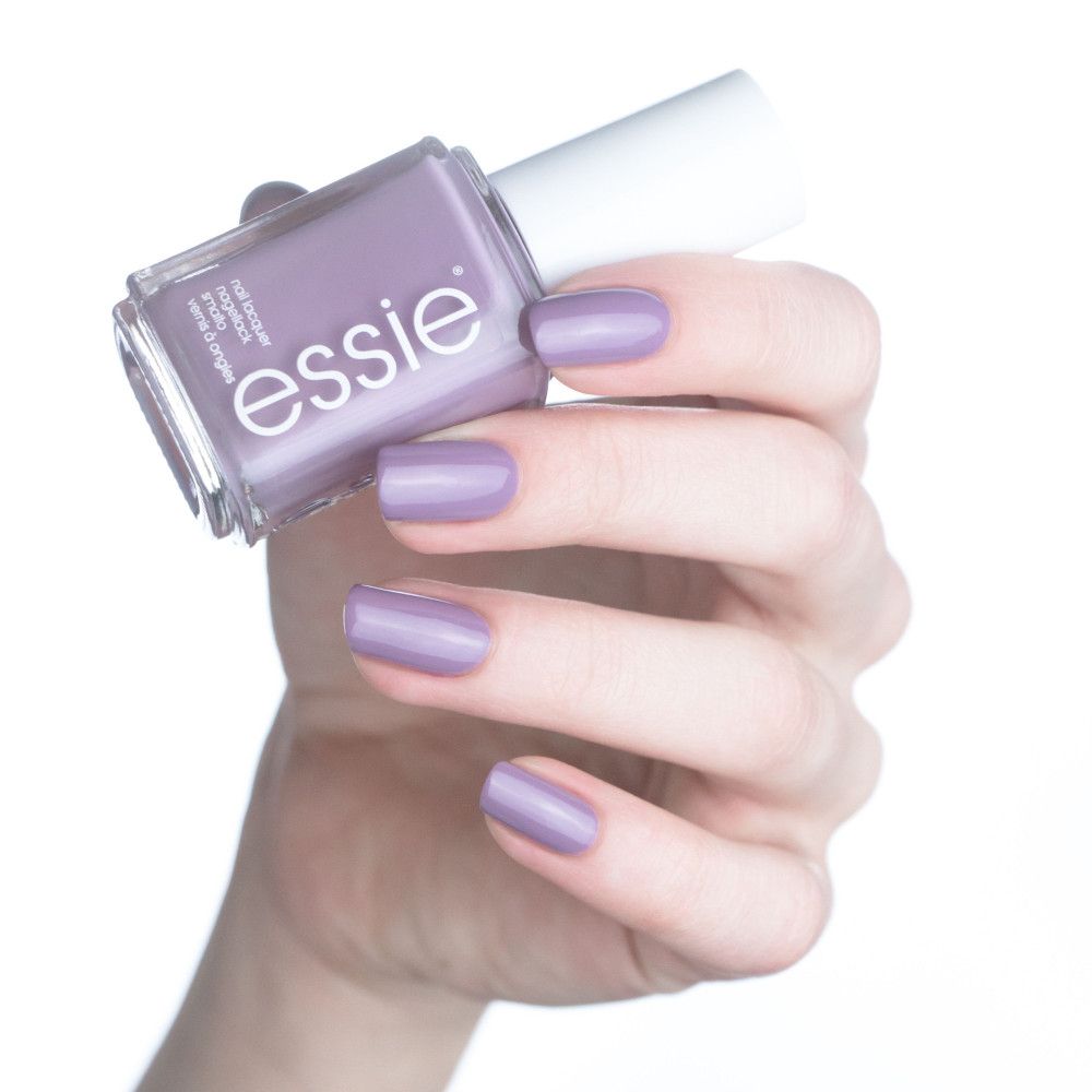 Essie nagellak, flesje en lichtpaarse gelakte nagels. Hand houdt flesje vast, nagels gelakt.