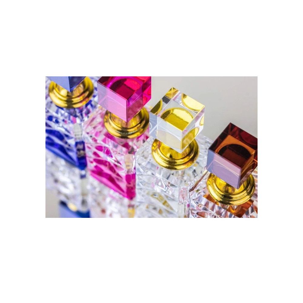 Rangée de flacons de parfum avec bouchons carrés colorés et cols dorés.
