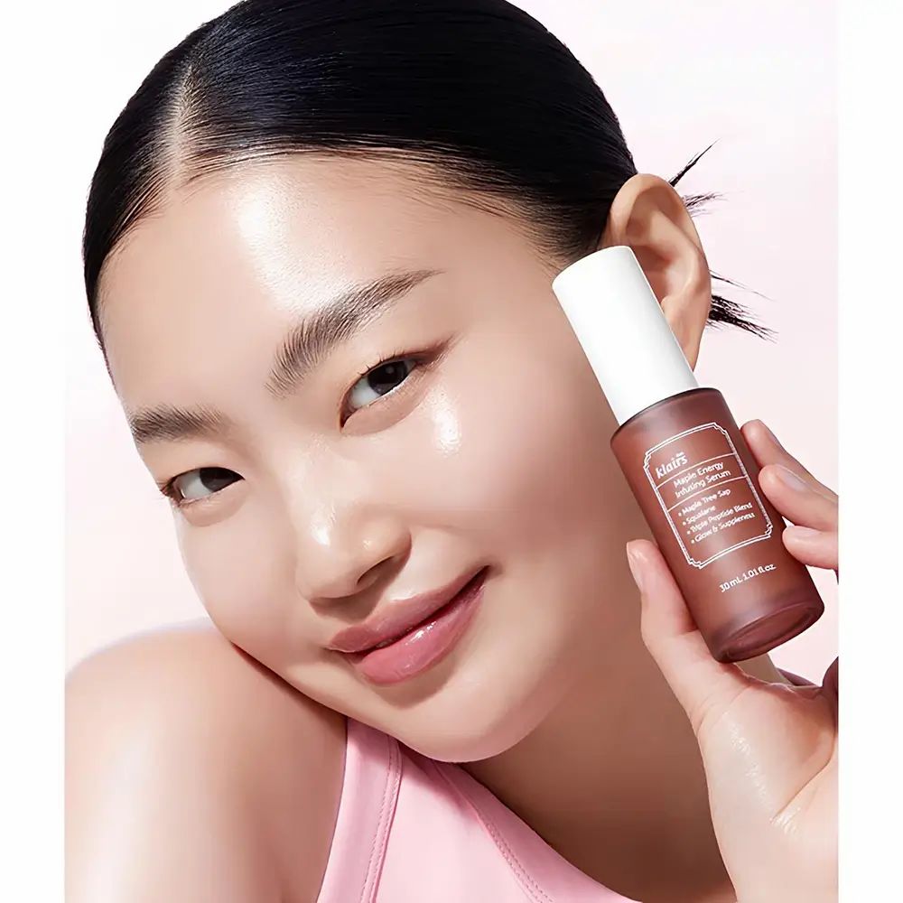 Vrouw houdt een bruine fles vast. Opschrift: klairs Maple Energy Infusing Serum. 30 ml.