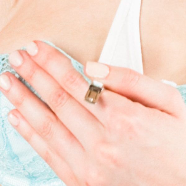 Close-up van een hand die een lichtblauwe BH aanraakt. De BH heeft kant. Ring aan de vinger.