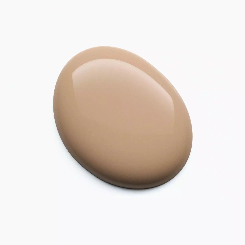 Goutte de vernis à ongles beige sur fond blanc. Surface brillante. Forme ovale.