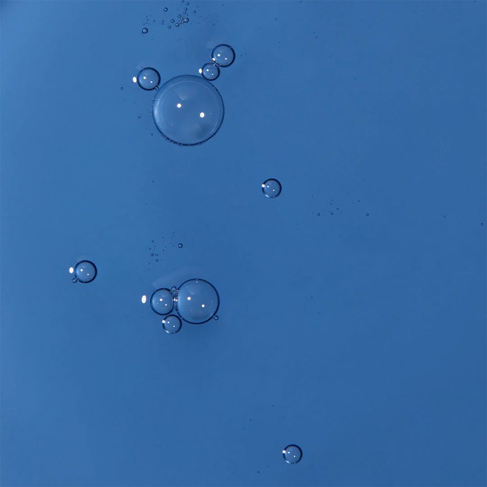 Close-up van blauwe serum bubbels op blauwe achtergrond.
