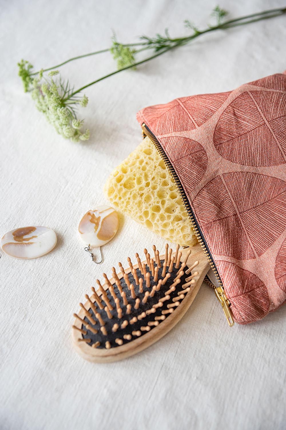 Open make-uptasje met bladerenpatroon. Bevat spons en haarborstel. Roze-beige tint.