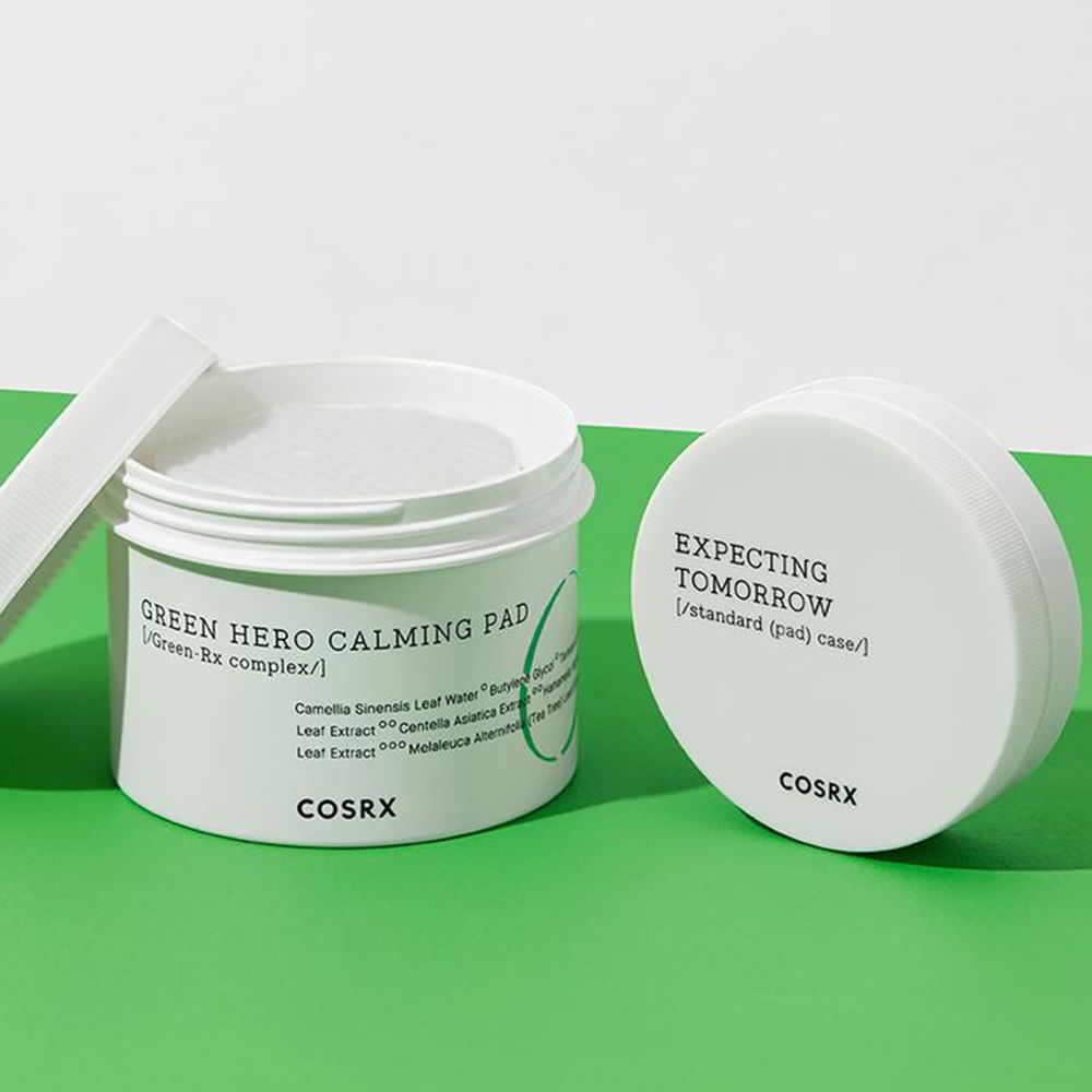 Witte pot met pads en deksel. Opschrift: Green Hero Calming Pad, COSRX. Groene achtergrond.