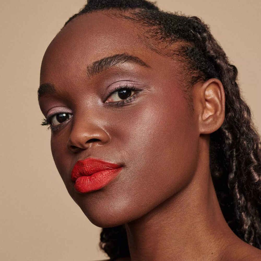 Portret van een vrouw met rode lippen. Donkere huid, vlechten.