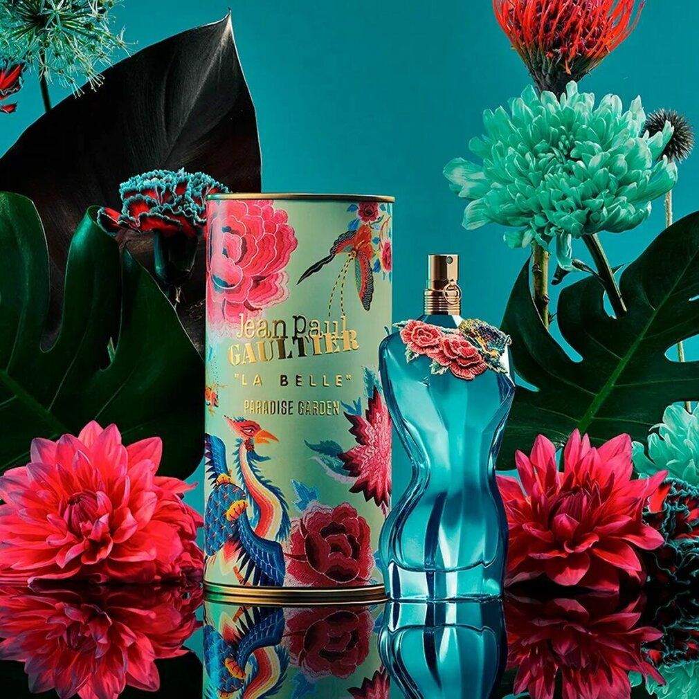 Flacon de parfum bleu en forme de corps féminin, décoré de fleurs. Fermeture dorée. À côté d'une boîte à motifs floraux.