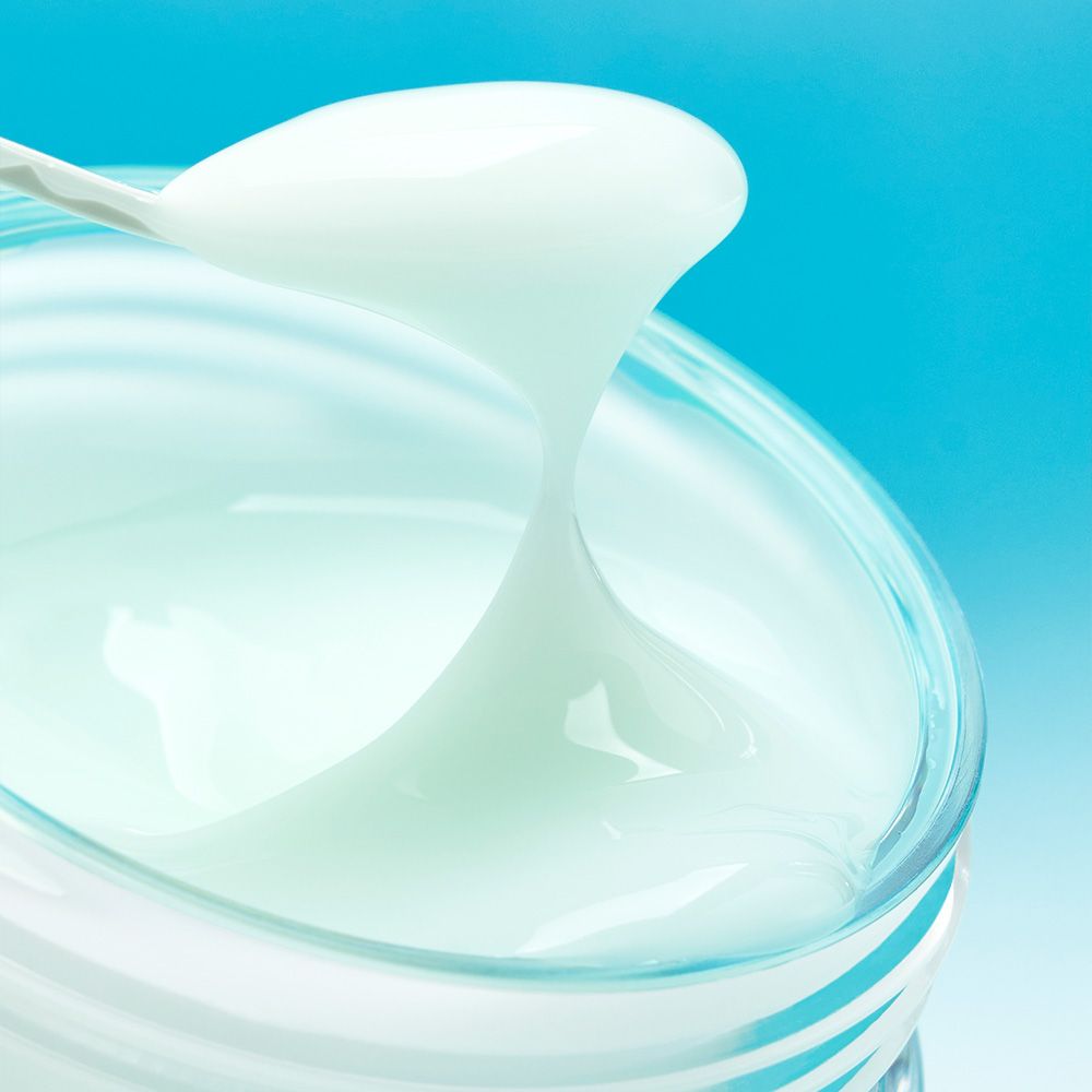 Une spatule prélève de la crème Numbuzin Pantothenic B5 d'un pot en verre.