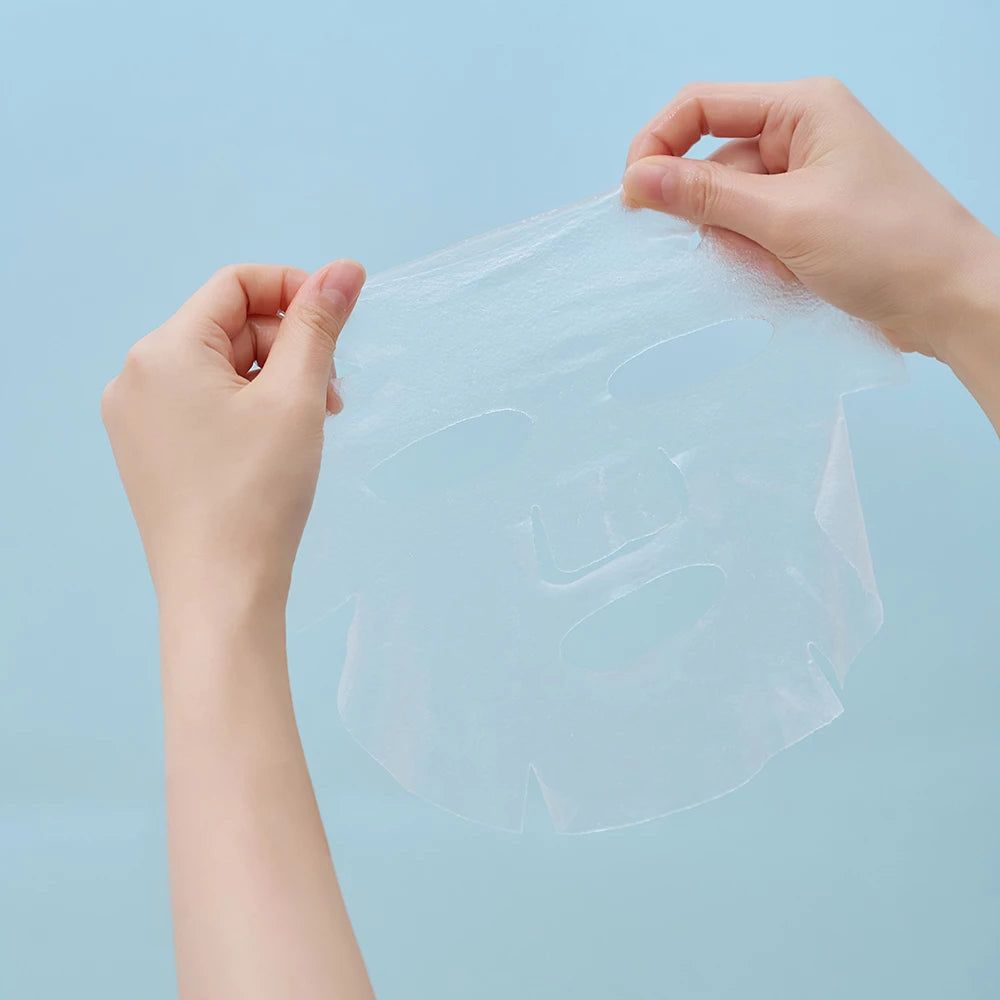 Mains tenant un masque hydratant transparent avec découpes pour les yeux et la bouche.