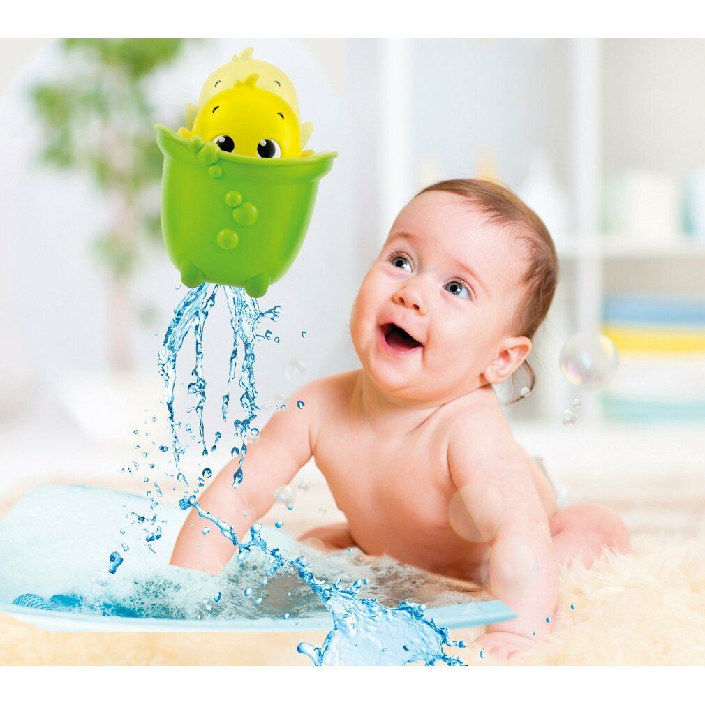 Een baby speelt met een geel kuiken-badspeeltje. Water spuit. Baby ligt in bad.