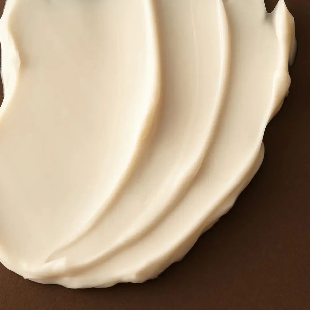 Gros plan de crème blanche crémeuse sur fond marron. Crème appliquée en vagues.