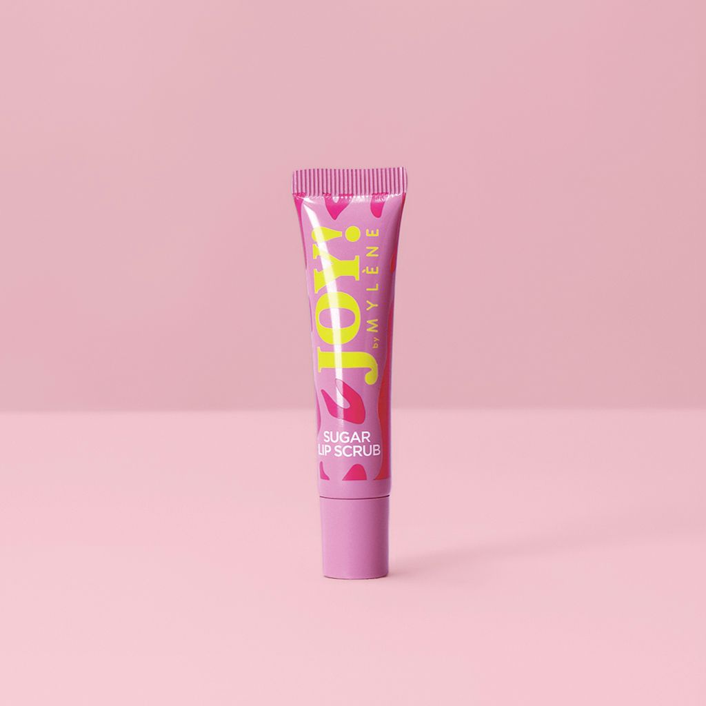 Mylène JOY! Sugar Lip Scrub dans un tube rose sur fond rose.