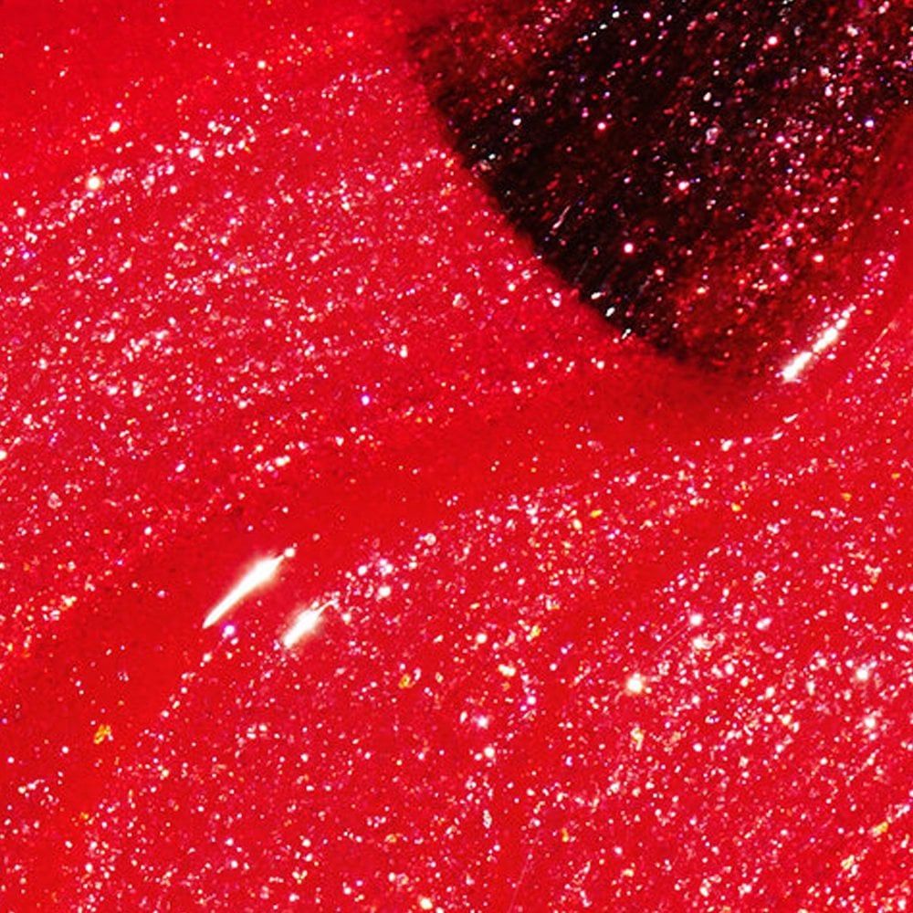 Rode nagellak met glitter. De kwast is gedeeltelijk zichtbaar.