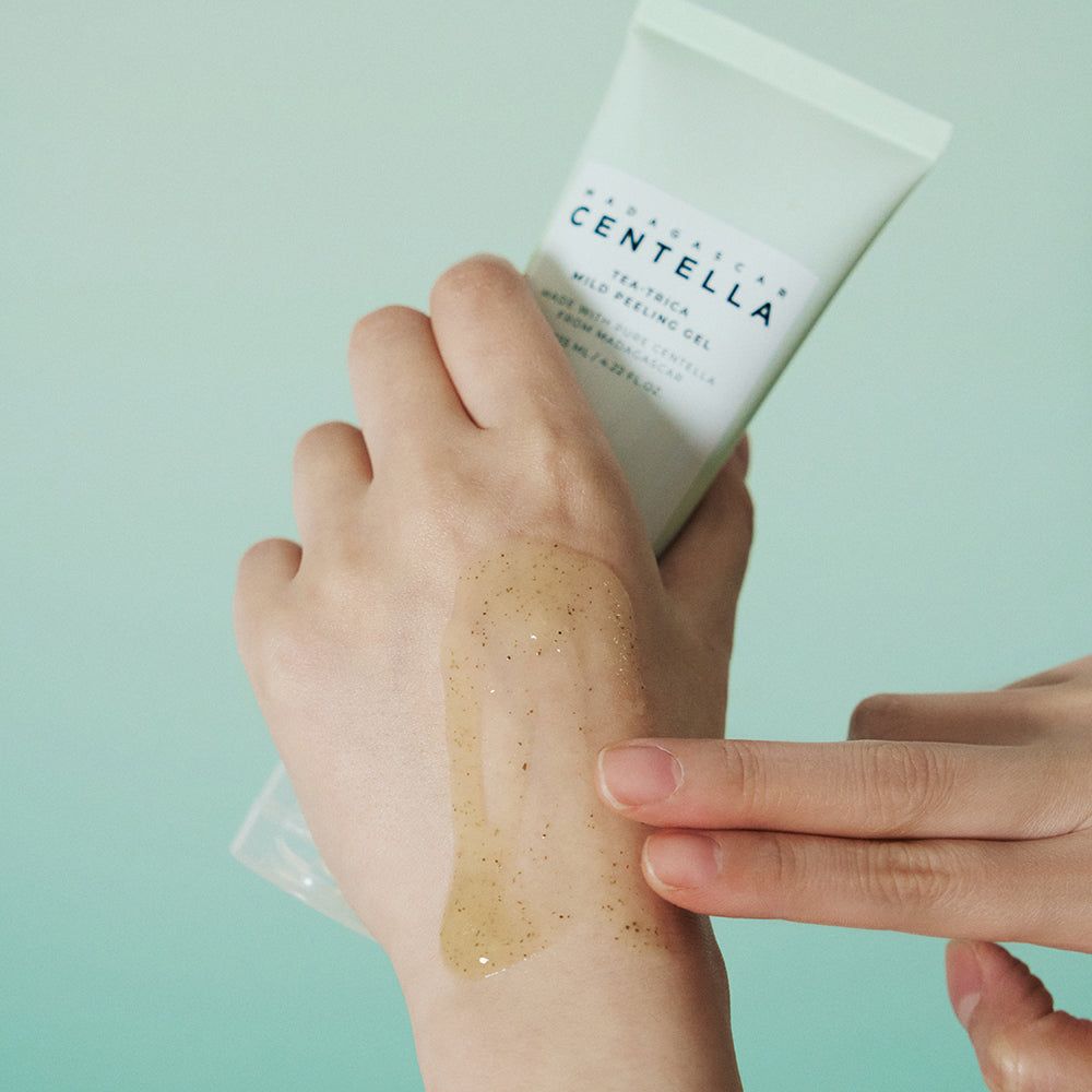 Hand met product. Opschrift: MADAGASCAR CENTELLA, Tea-Trica Mild Peeling Gel. Gel aangebracht op hand.