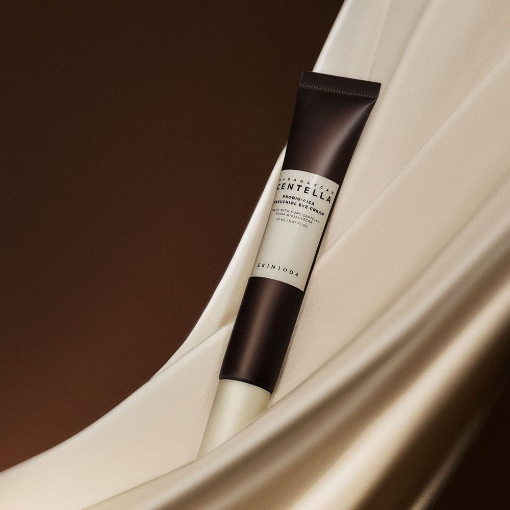 Crèmetube gedrapeerd op stof. Productnaam en merk zichtbaar.