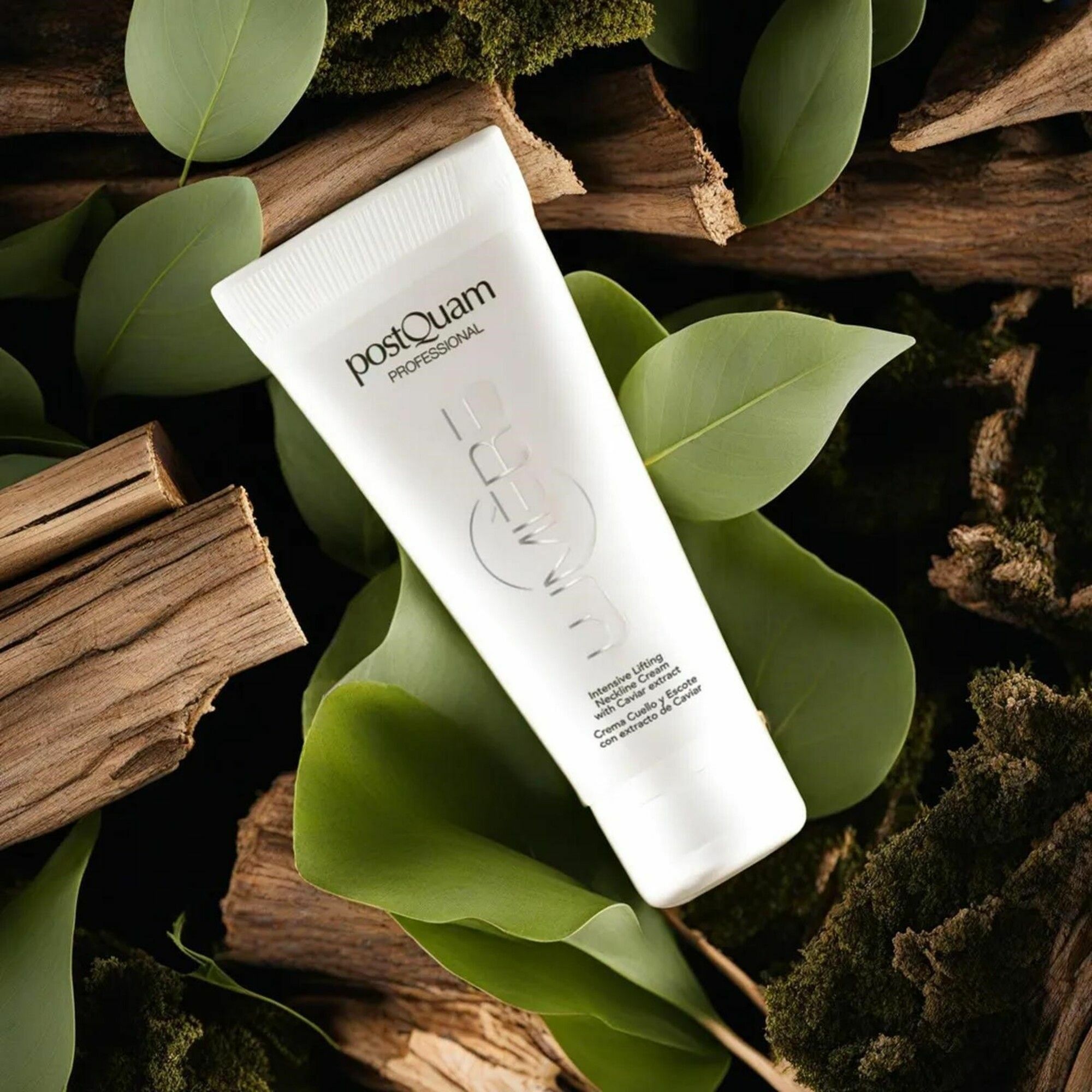 Tube blanc avec texte et logo. Posé sur des feuilles, du bois et de la mousse. Texte: PostQuam Professional, Caviar Lumiere.