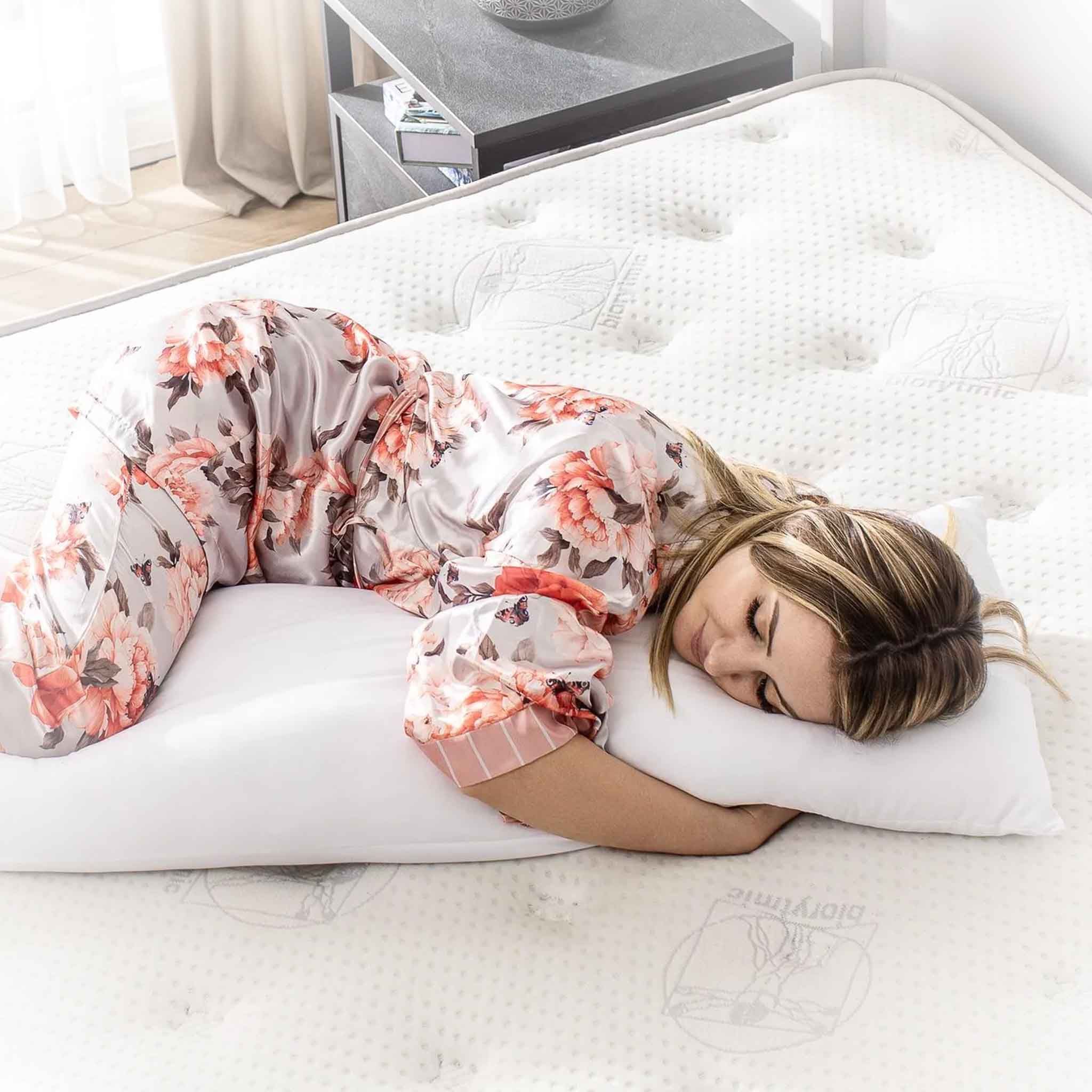 Femme allongée sur un lit, tête sur un oreiller blanc. Porte un pyjama.