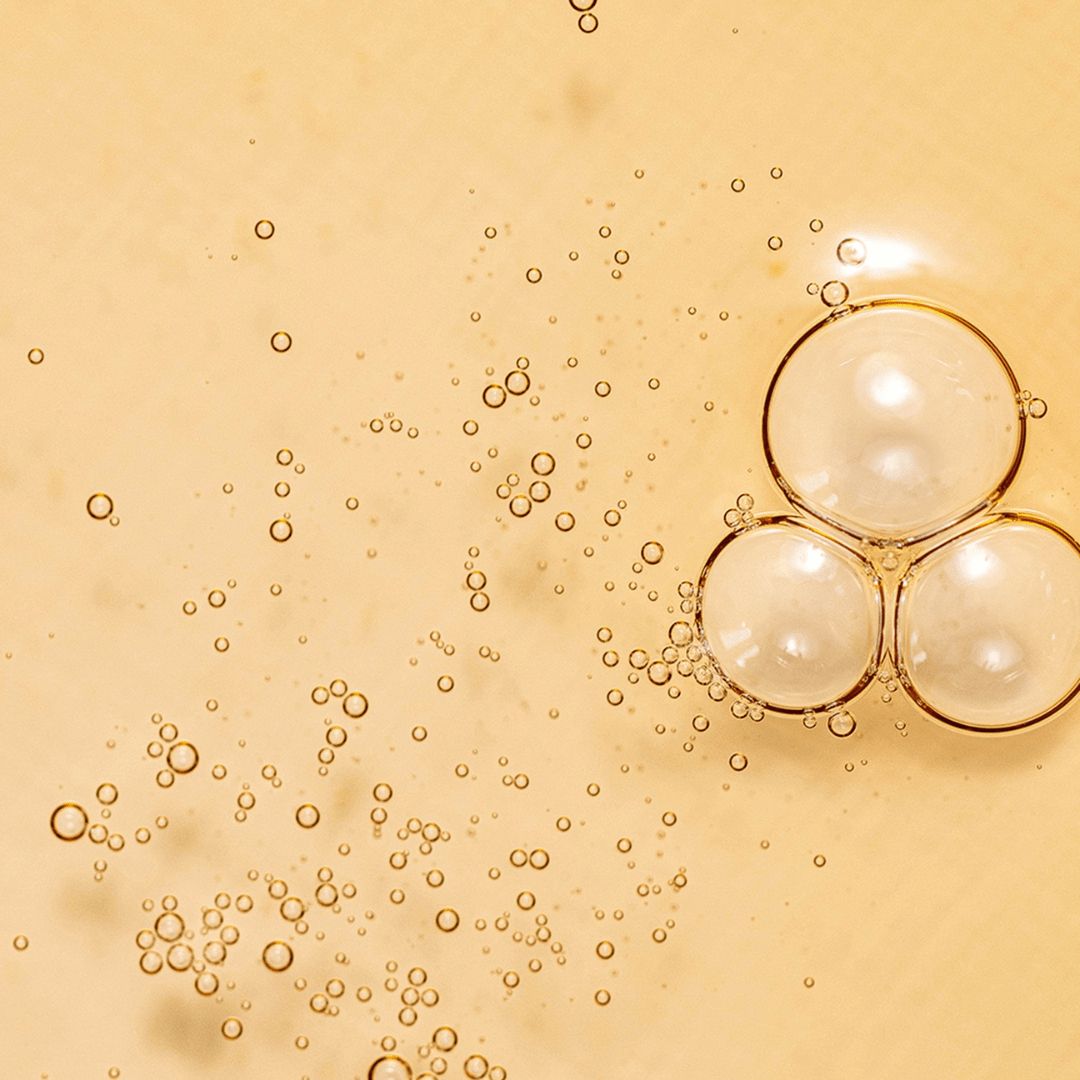 Gros plan de bulles dans un liquide jaunâtre. Quelques grosses bulles, d'autres petites.