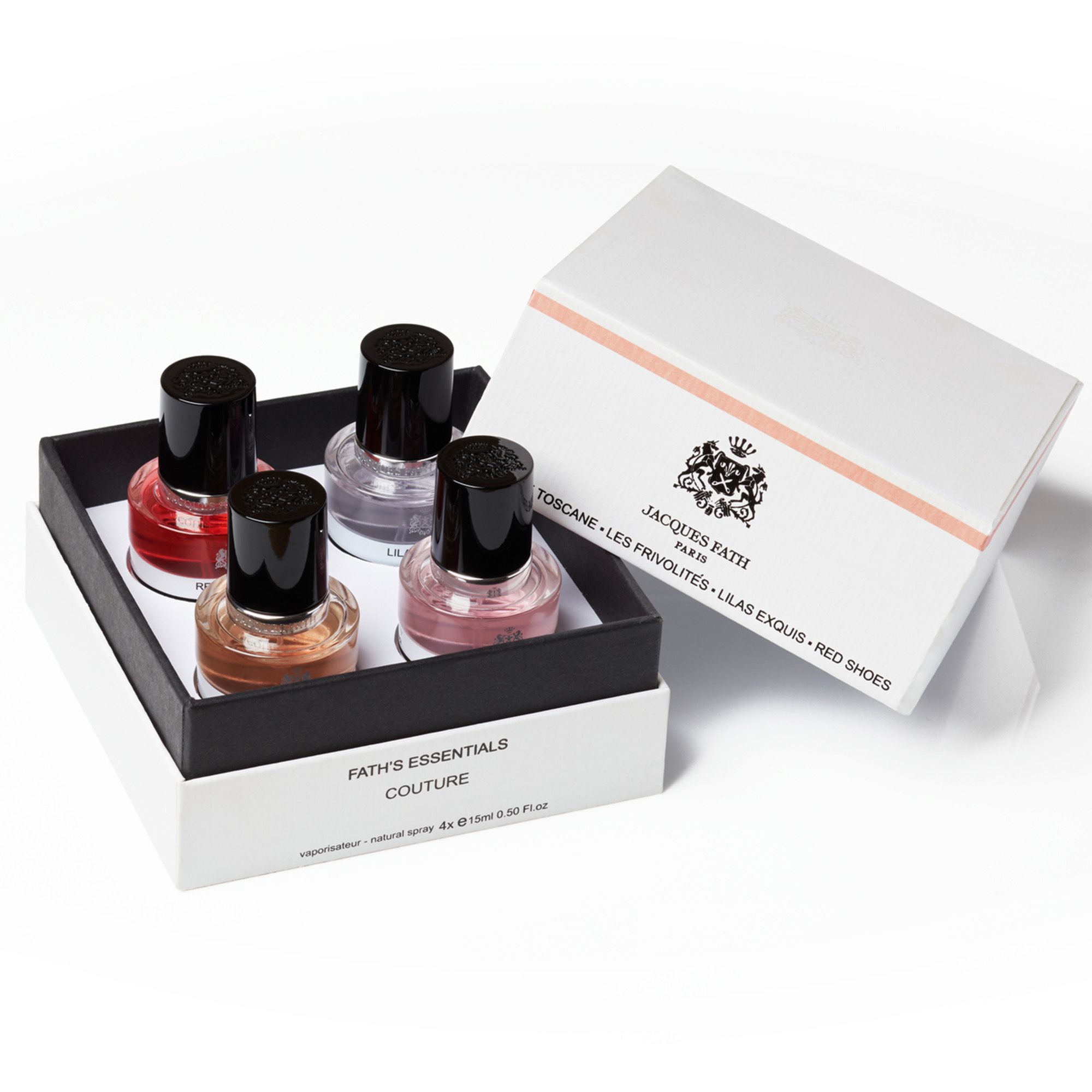Coffret cadeau avec quatre flacons de parfum. Bouchons noirs, liquides colorés. Inscription Fath's Essentials Couture. Boîte ouverte.