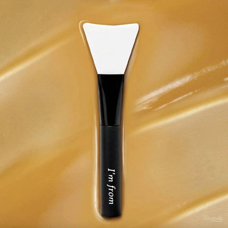 Siliconen spatel met zwarte handgreep. "I'm from" tekst op handgreep. Witte spatelkop. Op gouden achtergrond.