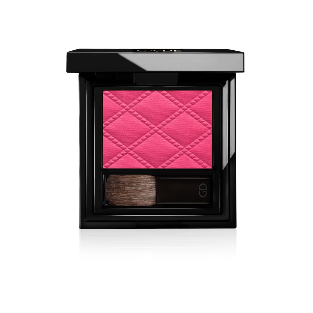 Boîtier de blush noir compact avec blush rose et pinceau. Le blush présente un motif en losanges en relief.