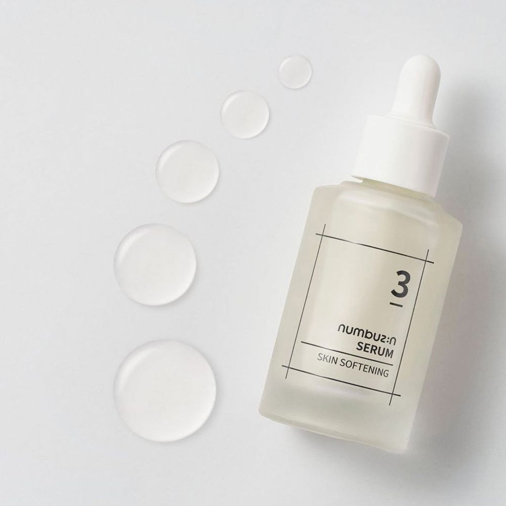 Serumfles met witte dop en pipet. Opschrift: 3, numbu:z:n SERUM SKIN SOFTENING. Druppels ernaast.