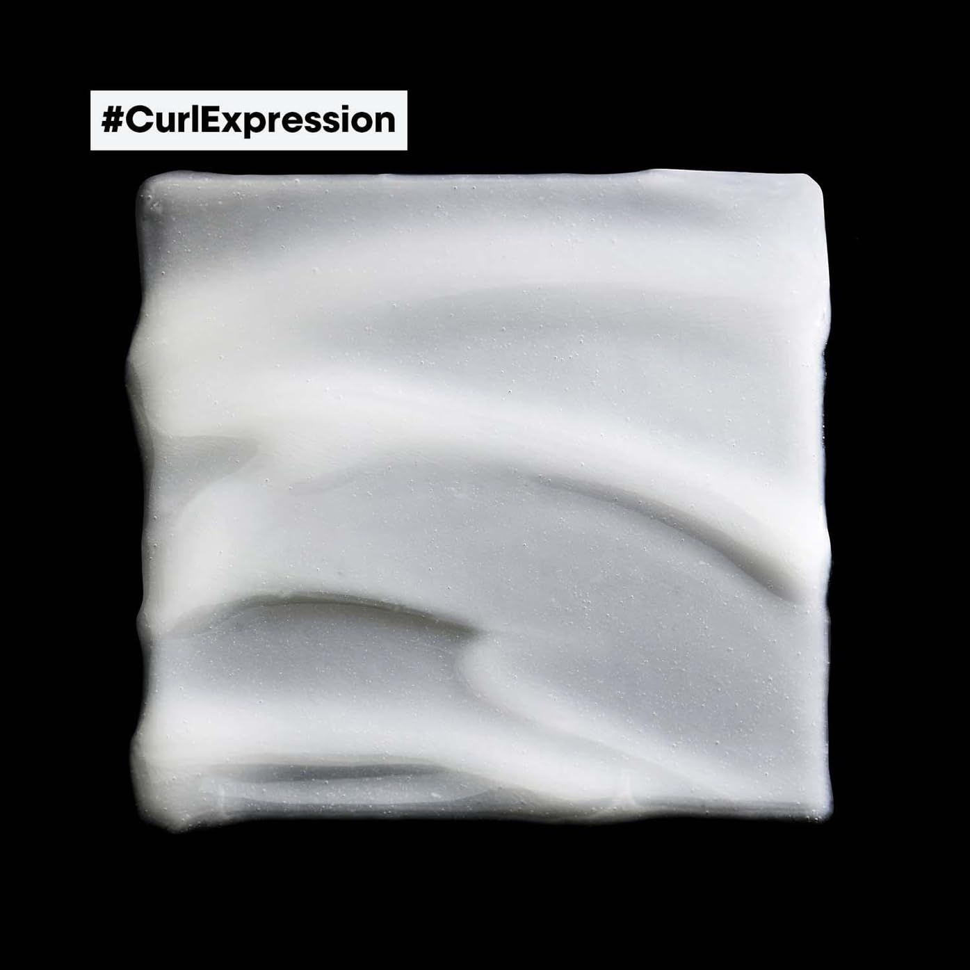 Vierkant monster van witte crème op zwarte achtergrond. De textuur is zichtbaar.