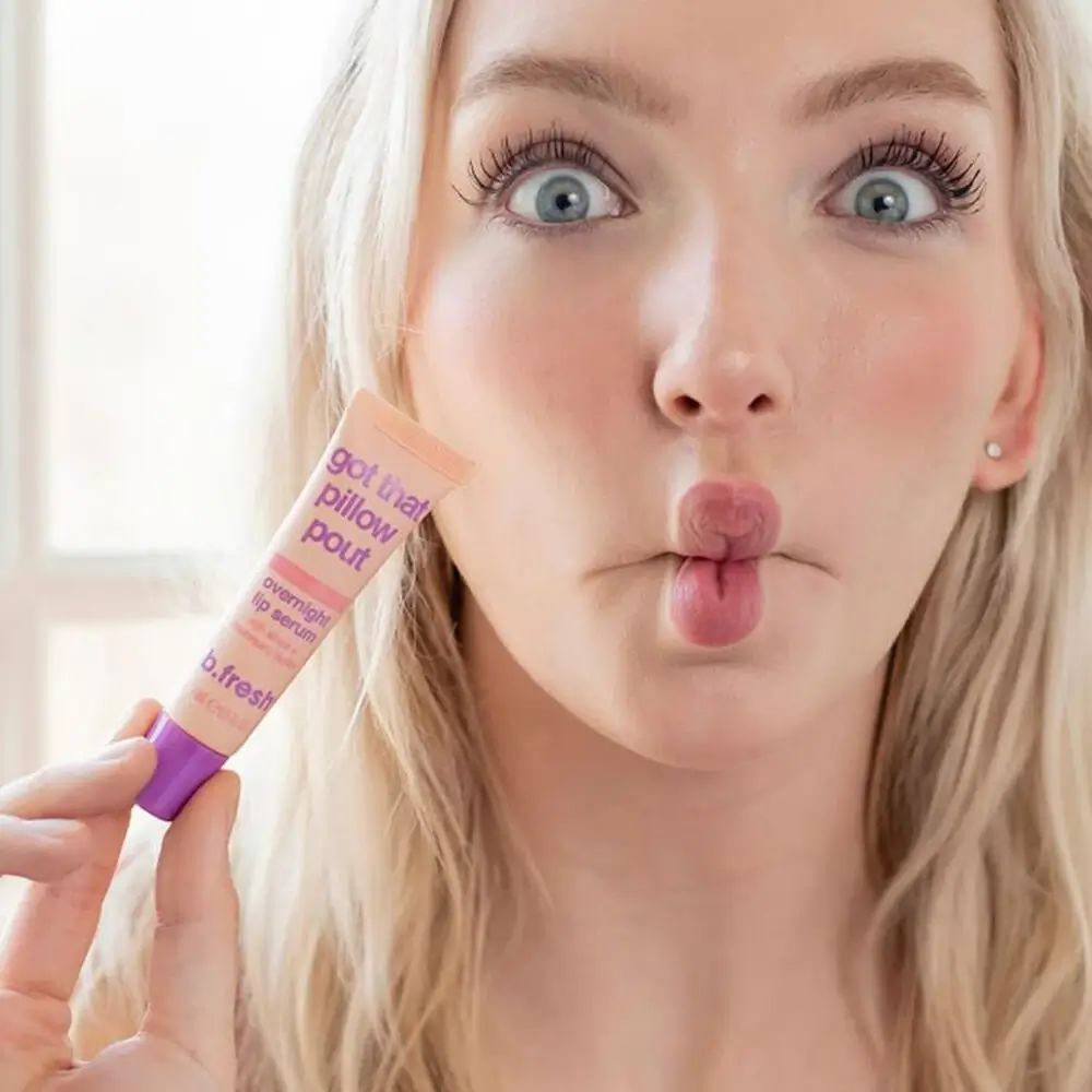 Blonde vrouw houdt tube vast. Opschrift: Got that pillow pout, overnight lip serum, b.fresh. Vrouw maakt kusmondje.