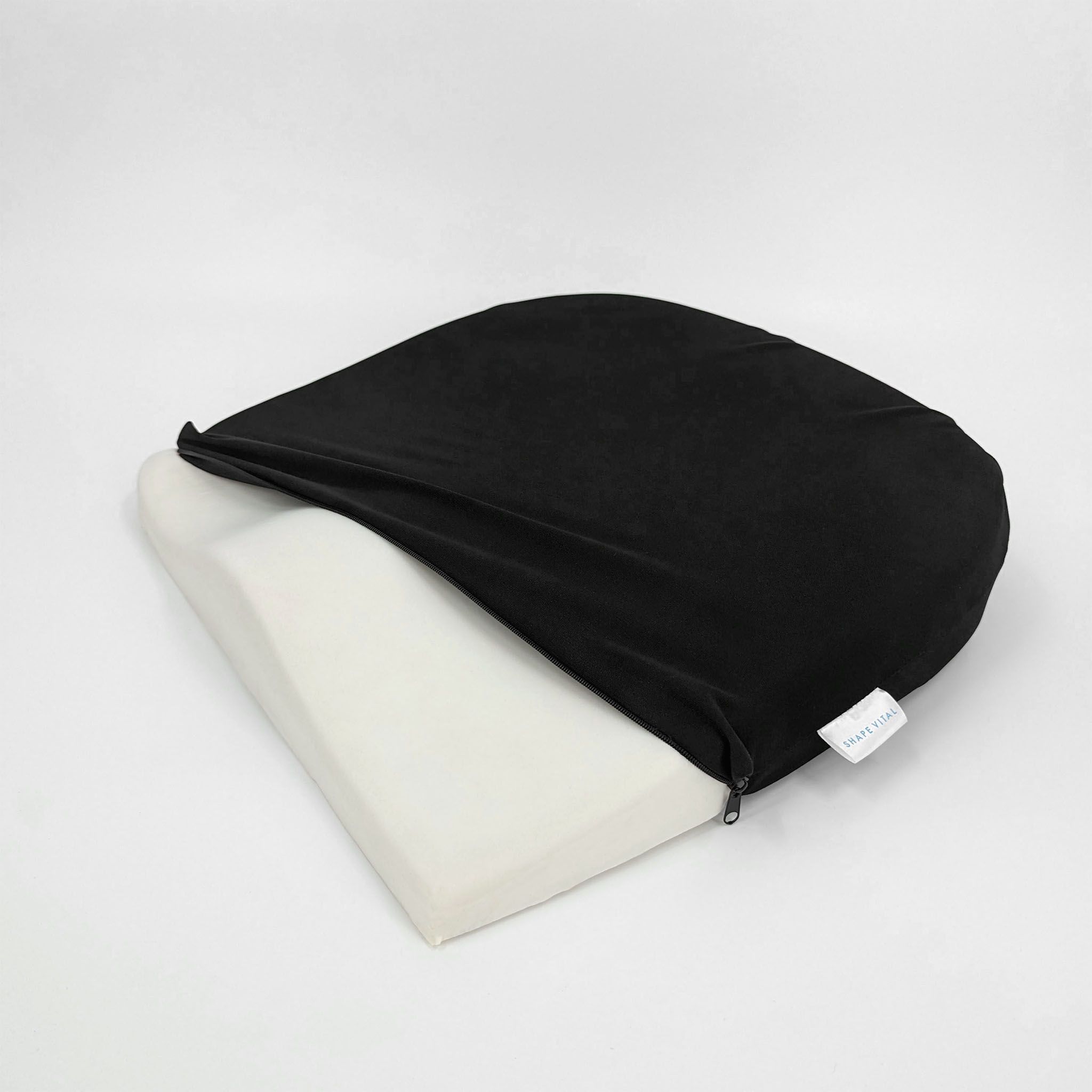 Coussin de siège en forme de coin, housse noire ouverte. Noyau en mousse visible. Fermeture éclair.