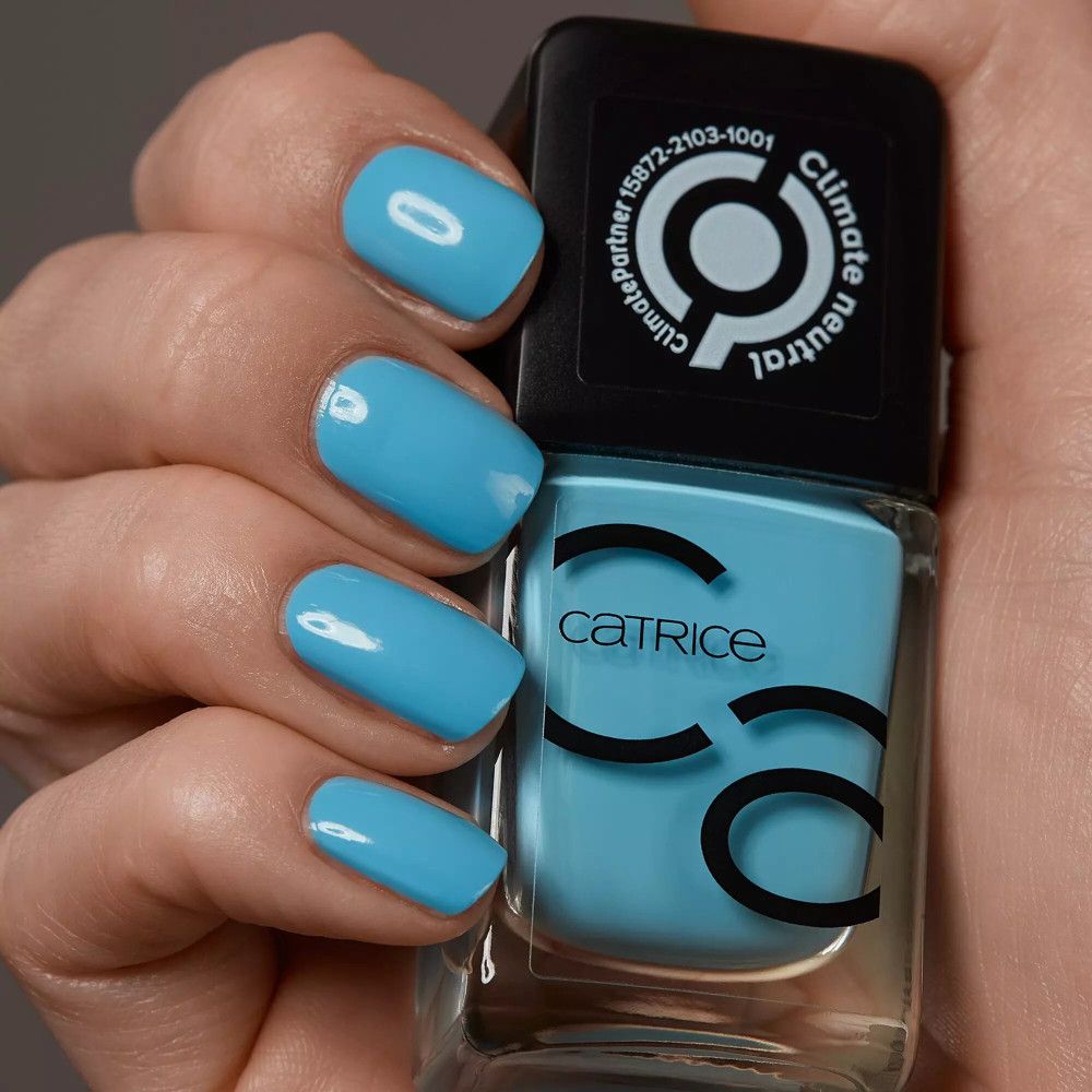 Vernis à ongles bleu clair et ongles vernis. Flacon Catrice. Logo Climate Partner.