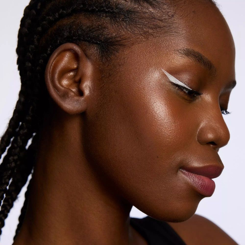 Gros plan sur un visage avec trait d'eyeliner blanc sur l'œil. Peau foncée.