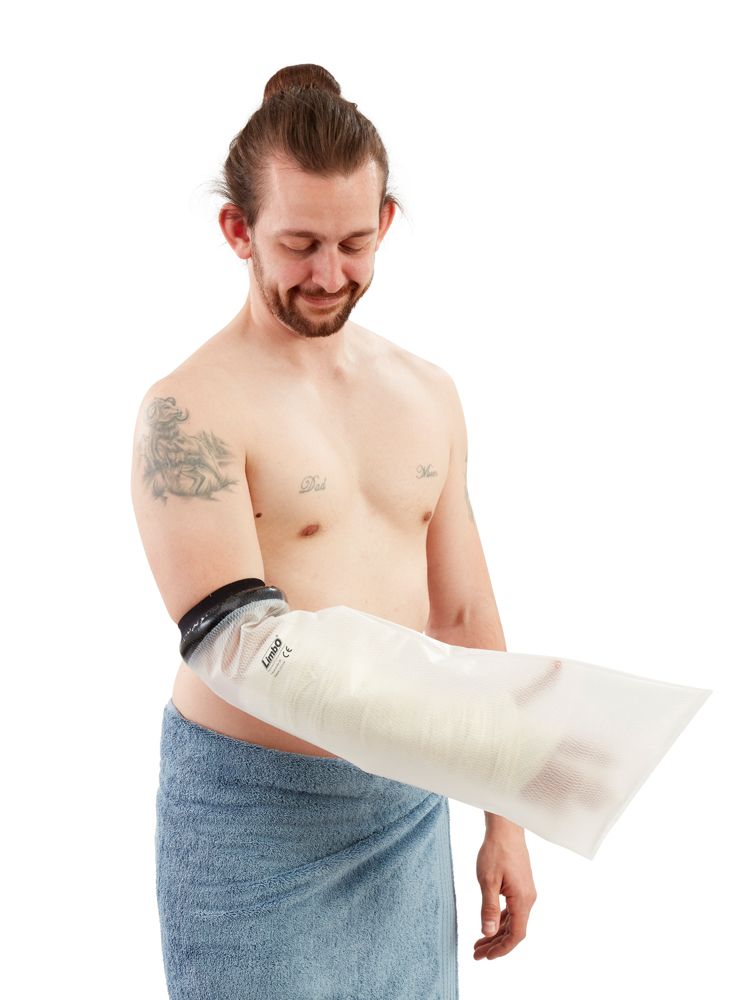 Protection pour plâtre, demi-bras, sur le bras d'une personne. Fermeture noire, enveloppe transparente. Personne avec tatouage et serviette.